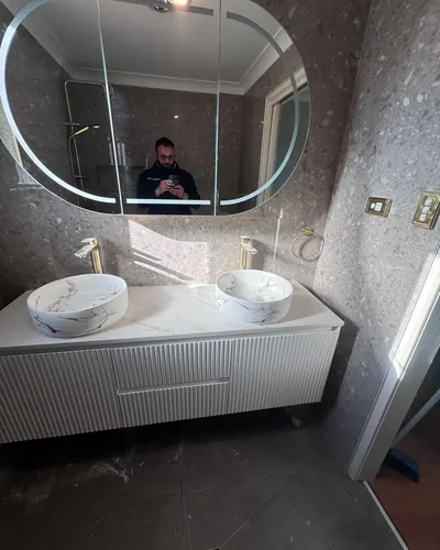 Double vanity fit-off with brushed gold mixers and an LED mirror cabinet