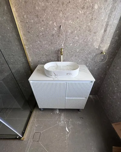 Basin and brushed gold mixer installed on a fluted vanity, water running