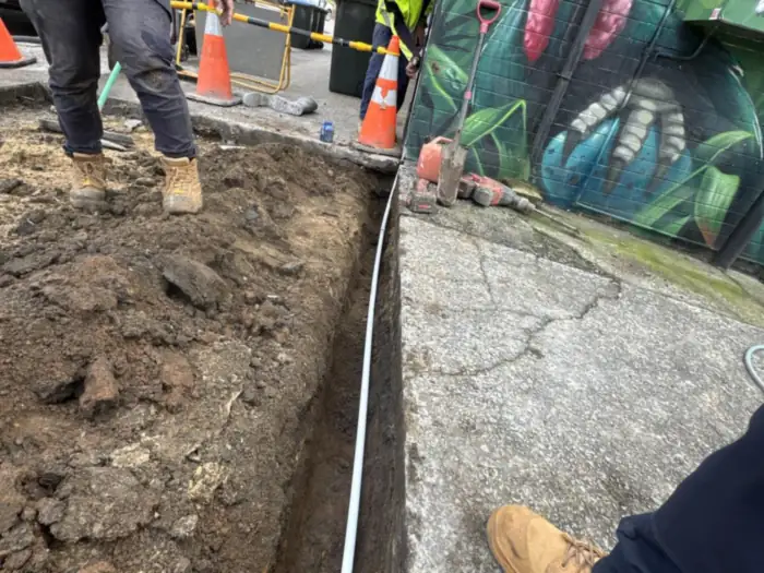 Communications conduit trenched along a footpath outside a shopping strip