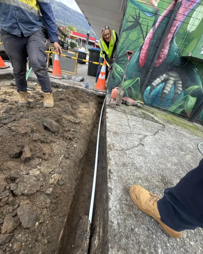 Comms conduit laid along a footpath trench in a shopping strip