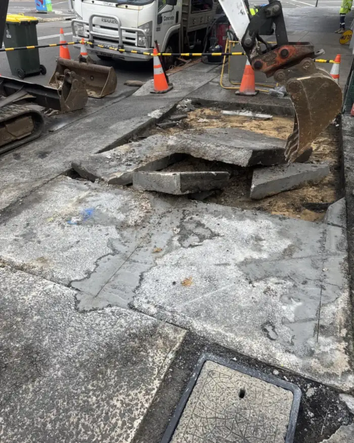 Mini excavator breaking out footpath concrete for a conduit run