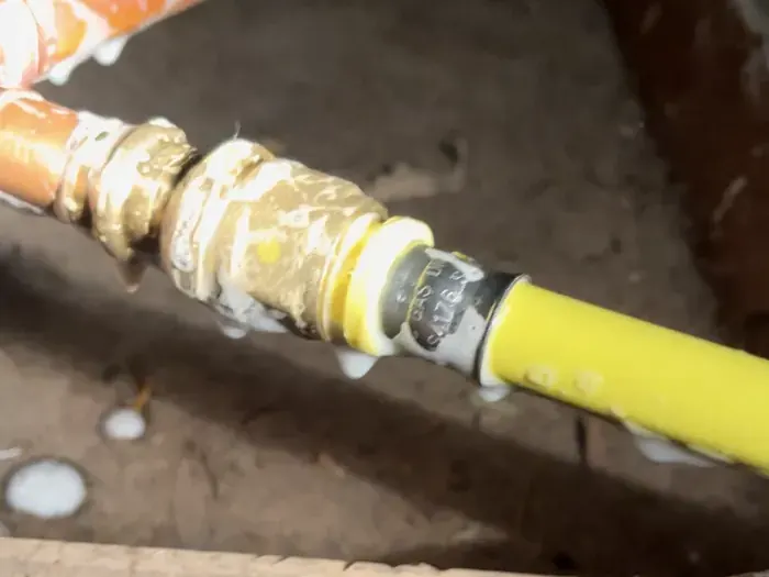 New yellow gas pipe joined to existing copper at a brass compression fitting, tested before it is closed up