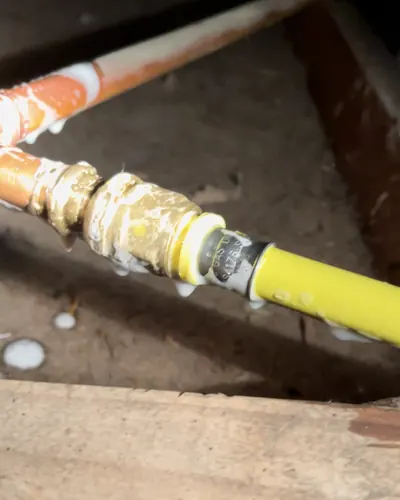 New yellow gas pipe joined to existing copper at a brass compression fitting, tested before it is closed up