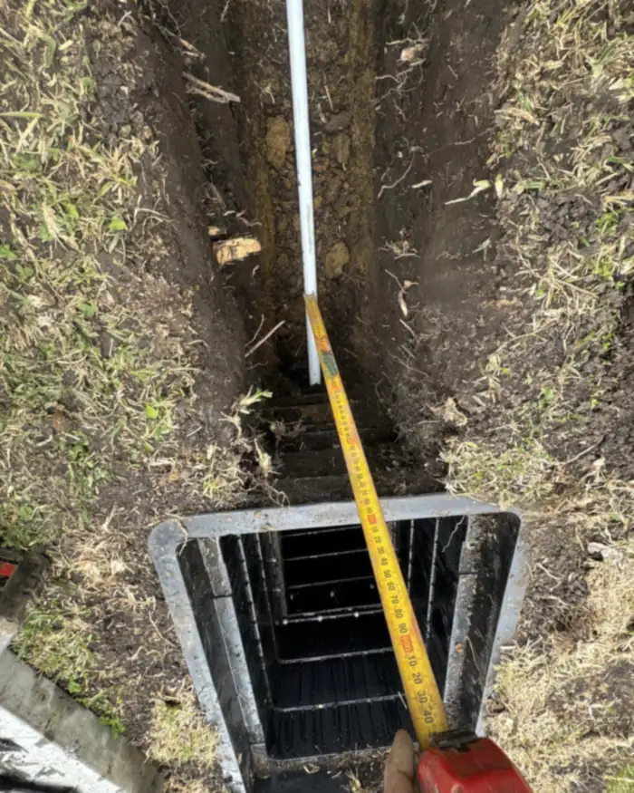 NBN lead-in conduit entering a pit, depth checked with a tape