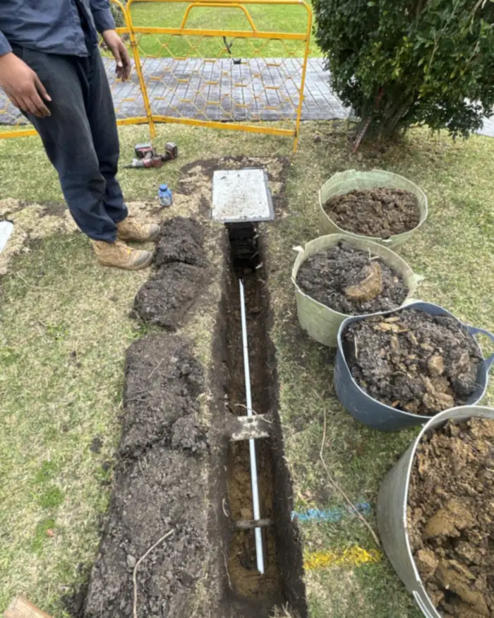 Conduit trenched to a new pit in a front yard with barriers up