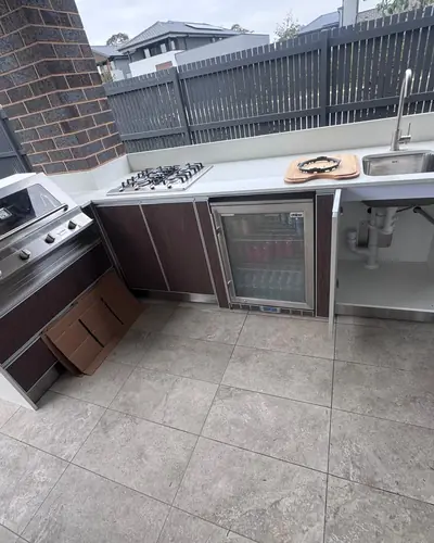 Outdoor kitchen with sink, gas cooktop and bar fridge plumbed in