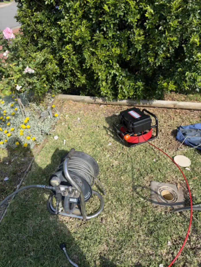 Jetter reel and drain camera set up at the sewer inspection opening in a front lawn, Wattle Grove